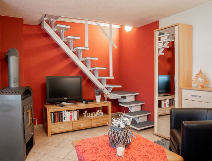 Wohnbereich mit Ofen, Fernseher und Treppe
